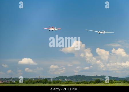 Rote Motorflugzeugablüge gleiten bei blau bewölktem Himmel in der Luft hoch Stockfoto