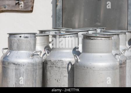 Mehrere leere silberne Kuhmilchdosen mit Deckel Stockfoto