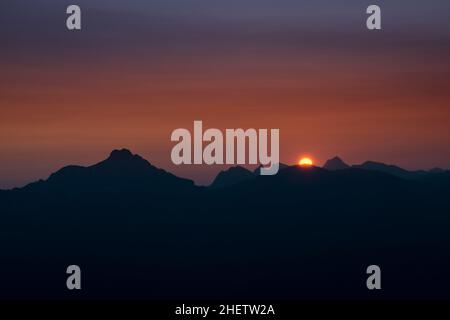 Die Sonne geht über den Tiroler Bergen mit orangefarbenem Himmel auf Stockfoto