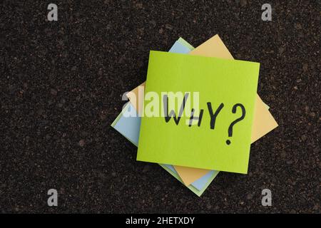 Ein Stapel von bunten Haftnotizen mit der Warum-Frage auf einem Korkbrett. Nahaufnahme. Stockfoto