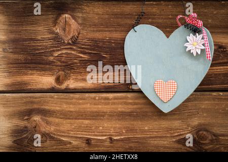 Hölzernes graues Herz mit Edelweiß auf sonnenverbrannten Holzplanken Stockfoto