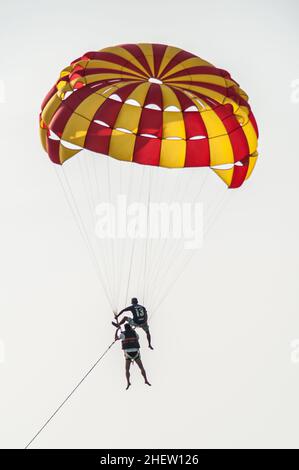 PHUKET, THAILAND - 13. MÄRZ 2018. Tourist mit Tauchlehrer, der im Fallschirm über den klaren Himmel fliegt. Redaktionelle Tagesaufnahme Stockfoto