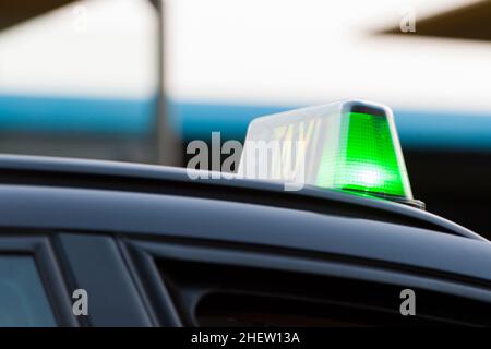 Nahaufnahme einer grünen Ampel an einem Taxi, die anzeigt, dass es gemietet werden kann, da es in der Schlange wartet Stockfoto