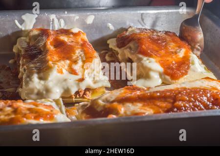 Lasagne in einer Aluminiumpfanne, Spachtel nimmt ein Stück der Pfanne, selektiver Fokus Stockfoto