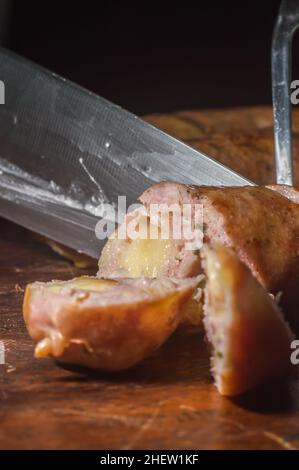 Wurst in Scheiben geschnitten ​​on ein Holzbrett mit Käsestücken im Inneren der Wurst, selektive Fokus und Kopierer Platz Stockfoto