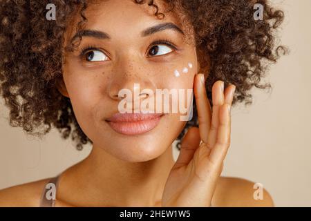 Nette Dame mit kosmetischen Produkt im Studio Stockfoto