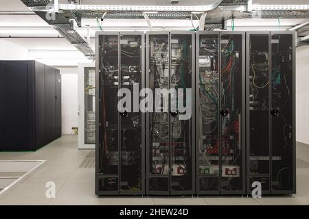 Rückseite der angeordneten schwarzen Server-Racks in einem kleinen Computerraum Stockfoto