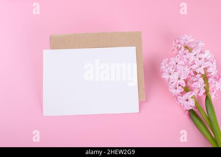 Unbeschriftete Hochzeitseinladung Briefpapier-Karte Mockup mit Umschlag auf rosa Hintergrund mit Hyazinthe-Blumen Stockfoto