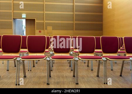 Rote gepolsterte Stühle, die bereit sind, in einem Konzertsaal Platz zu nehmen Stockfoto