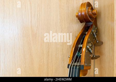 Hals eines Cellos, der an einer Holzwand angelehnt ist Stockfoto