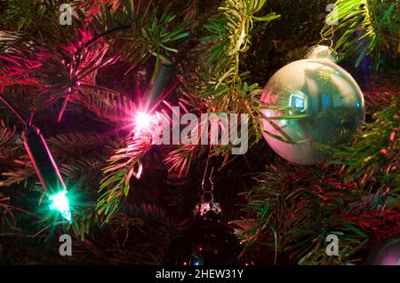 Detail eines weihnachtsbaumknotens mit Kugel und farbigen Lichtern Stockfoto