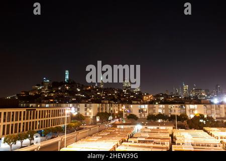 Nachtpanorama des san francisco Coit Tower und viele orangefarbene Busse vorne Stockfoto