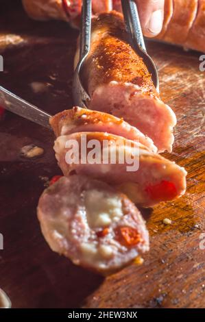 Wurst und Paprika, handwerkliche Wurst mit Käse und Pfeffer auf einem Holzbrett, Kopierraum und selektiver Fokus Stockfoto