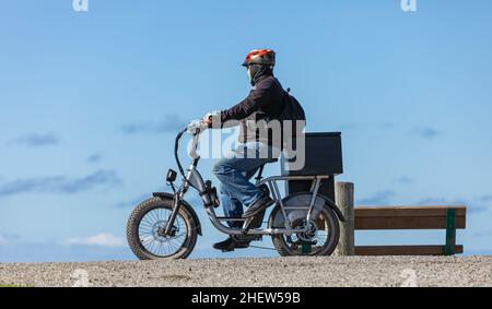 Mann auf E-Bike im blauen Himmel Hintergrund Fahrt auf dem Radweg im Park-Oktober 11,2021-Richmond BC, Kanada. Straßenansicht, Kopie spce für Text, tr Stockfoto