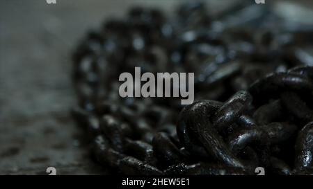 Nahaufnahme für schwarze Ketten aus Eisen in der Werkstatt und industrielle Hintergründe verschiedener Werkzeugmaschinen. Ein Haufen Ketten und Holzbearbeitungsfabrik Stockfoto