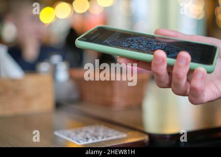 Nahaufnahme der Gäste, die eine Mahlzeit im Restaurant bestellen, während der QR-Code mit dem Mobiltelefon gescannt wird, um ein Online-Menü zu erhalten. Stockfoto