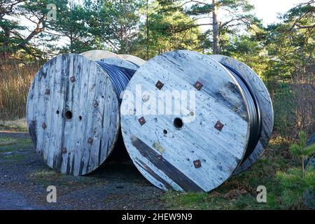 Große Holzspulen mit Spiralkabel im Freien. Stockfoto