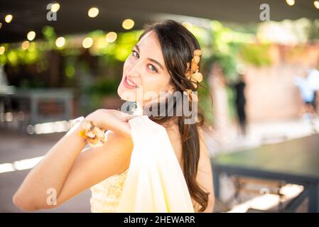 Junge Frau in einem gelben Partykleid, lächelnd vor der Kamera. Hochzeitsgast. Stockfoto