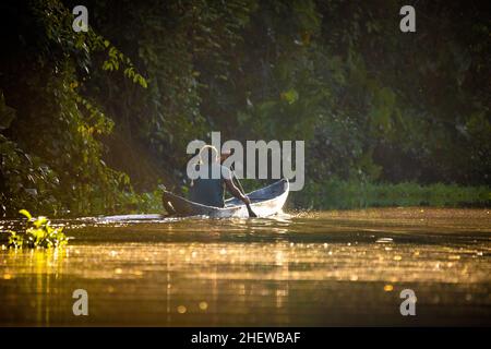 Malerische Aussicht auf Fischer im Kanu bei orangefarbenem Sonnenaufgang auf dem Fluss Stockfoto