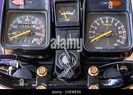 Schwarzes analoges Motorrad-Armaturenbrettinstrument mit einem Schlüssel, der auf der flachen Ansicht von oben hängt, und einem gelben Messgerät, das den Tachometer, den Tachometer, Stockfoto