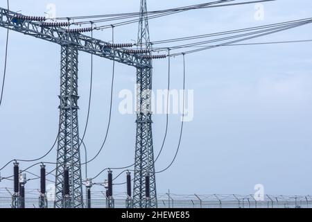 Unter dem C steht ein massiver und hoher Metallturm am Kraftwerk, der bereit ist, die Spannungsenergie mit den gedehnten Kabeln darüber zu verteilen Stockfoto