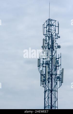 Hoher Telekommunikationsturm oder Sender, der das Internet und mobile Daten im Hintergrund des bewölkten Himmels überträgt Stockfoto