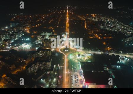 Luftaufnahme von Hochhäusern und hell beleuchteten Kreisverkehr Kreuzung auf der städtischen Straße in der Stadt Wohngebiet in der Nacht. Dunkles Ur Stockfoto