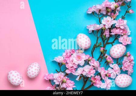 Osterhintergrund mit Ostereiern mit Punktmuster, pastellrosa und blauem Papierschablone, Grußkarte mit Platz für Text. Künstliche Pflanzen decorati Stockfoto