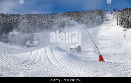 12. Januar 2022, Sachsen, Oberwiesenthal: Unter einer Schneelanze hat sich bereits ein großer Schneehaufen gesammelt. Am Samstag (15,01.) startet die diesjährige Skisaison am Fichtelberg offiziell. Aufgrund von Corona ist das Skigebiet nur für geimpfte und geborgene Skifahrer geöffnet (2G); beim Anstehen am Lift und im Lift selbst muss eine Maske getragen werden. Der Status von 2G wird vor dem Kauf des Skipasses sowie im Skigebiet überprüft. Zu diesem Zweck werden auf dem Parkplatz der Seilbahn Fichtelberg eine Kontrollstelle und eine zentrale Verkaufsstelle für Lifttickets eingerichtet. Foto: Jan Woitas/dpa-Zentralb Stockfoto