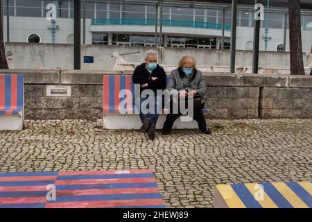 Ein älteres Paar mit Gesichtsmasken als Vorsichtsmaßnahme gegen die Ausbreitung von Covid-19, das auf einer Bank auf dem Boulevard des Parque das NaÁ?es in Lissabon sitzt. Stockfoto