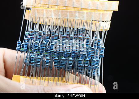 Satz von elektronischen Widerständen mit festem Wert in der Hand gehalten, isoliert auf schwarzem Hintergrund Stockfoto