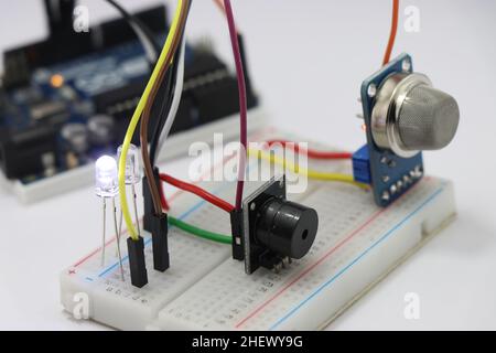 Seitenansicht verschiedener elektronischer Komponenten auf einer Breadboard-Schaltung mit Mikrocontroller im Hintergrund, die das Konzept des Prototyping zeigt Stockfoto