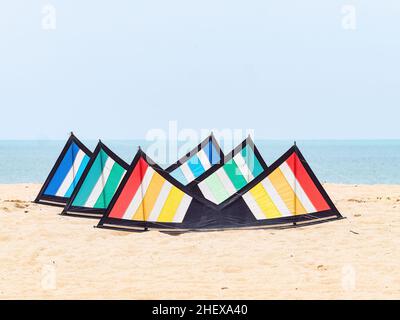 Ein Stapel von drei Quadline-Sportdrachen in roten, grünen und blauen Farben am Strand in Kelantan, Malaysia. Stockfoto