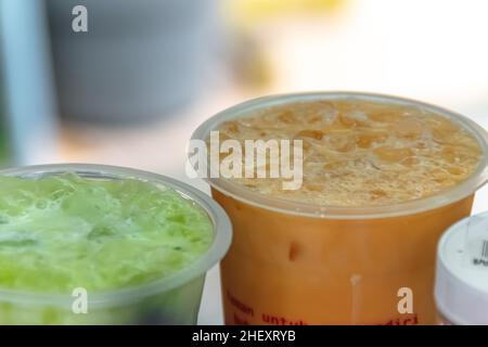 Nahaufnahme von frischen und kalten traditionellen asiatischen Milchteegetränken mit rasierten Eiswürfeln, die einpacken und servieren, mit verschwommenem und weichem Hintergrund Stockfoto