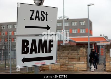 Halberstadt, Deutschland. 10th Januar 2022. Im Eingangsbereich der Zentrale Anlaufstelle für Asylsuchende (ZAST) und des Bundesamtes für Migration und Flüchtlinge (BAMF) stehen Wegweiser. Das ZAST ist in einer ehemaligen NVA-Kaserne untergebracht, in der früher die DDR-Grenztruppen ausgebildet wurden. Quelle: Matthias Bein/dpa-Zentralbild/dpa/Alamy Live News Stockfoto