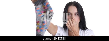 Porträt einer jungen Frau, die die Nase bedeckt und die Socke in der Hand in Nahaufnahme hält Stockfoto