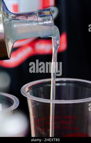 Gießen eines Litschi-Sirups in ein transparentes Kunststoffglas mit einem verschwommenen und weichen fokussierten Hintergrund Stockfoto