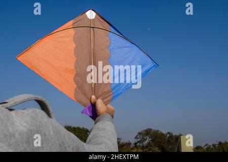 Boy Flying Kite auf Indian Kite Flying Festival von Makarsankranti, Lohri, Pongal oder Uttarayan mit klarem Himmel Hintergrund. Leerzeichen zum Schreiben von Text oder f Stockfoto