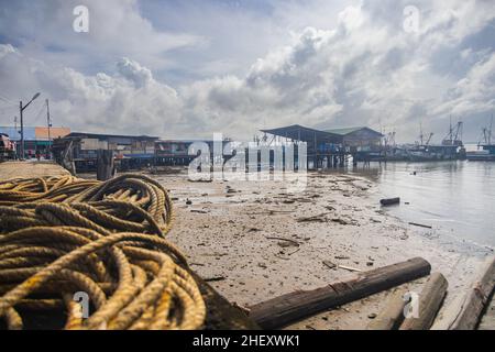 Sandakan, Malaysia - 06. Januar 2022: Fischerdorf in der Nähe des Zentrums von Sandakan, Borneo. Arme Hütten auf Stelzen über dem Küstenwasser am Ufer. Stockfoto