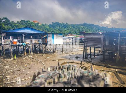 Sandakan, Malaysia - 06. Januar 2022: Fischerdorf in der Nähe des Zentrums von Sandakan, Borneo. Arme Hütten auf Stelzen über dem Küstenwasser am Ufer. Stockfoto