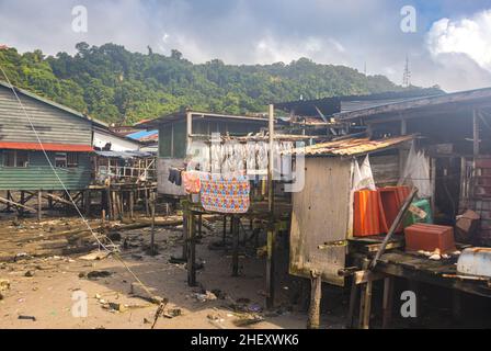 Sandakan, Malaysia - 06. Januar 2022: Fischerdorf in der Nähe des Zentrums von Sandakan, Borneo. Arme Hütten auf Stelzen über dem Küstenwasser am Ufer. Stockfoto