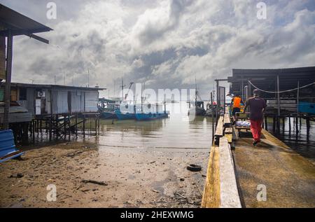 Sandakan, Malaysia - 06. Januar 2022: Fischerdorf in der Nähe des Zentrums von Sandakan, Borneo. Arme Hütten auf Stelzen über dem Küstenwasser am Ufer. Stockfoto