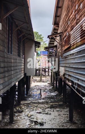 Sandakan, Malaysia - 06. Januar 2022: Fischerdorf in der Nähe des Zentrums von Sandakan, Borneo. Arme Hütten auf Stelzen über dem Küstenwasser am Ufer. Stockfoto