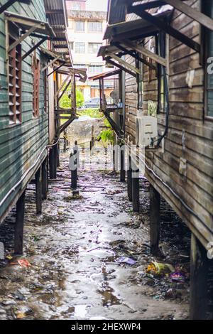 Sandakan, Malaysia - 06. Januar 2022: Fischerdorf in der Nähe des Zentrums von Sandakan, Borneo. Arme Hütten auf Stelzen über dem Küstenwasser am Ufer. Stockfoto