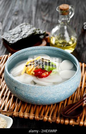 Tteokguk, traditionelle koreanische Suppe aus geschnittenem Reiskuchen und Brühe, serviert am Seollal Day oder am Neujahrsfest auf einem Holztisch Stockfoto