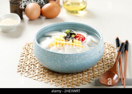 Tteokguk koreanische Reiskonditorei-Suppe für das seelische Neujahr, Topping mit Scheiben Ei, Chili und Sesamsamen Stockfoto