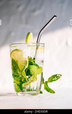 Mojito Cocktail aus Glas mit Limette, Eis und Minze serviert auf hellem Hintergrund Stockfoto