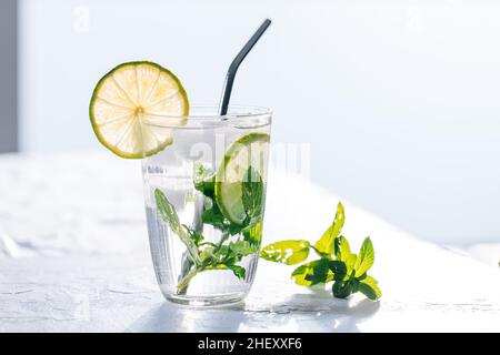 Mojito Cocktail aus Glas mit Limette, Eis und Minze serviert auf hellem Hintergrund Stockfoto