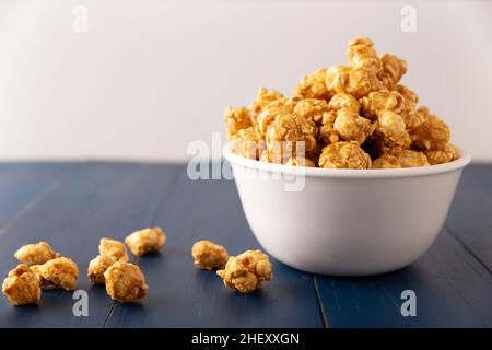 Karamell Popcorn in weißer Schale auf rustikalem blauen Holztisch. Nahaufnahme. Kopieren Sie Platz für Ihren Text Stockfoto