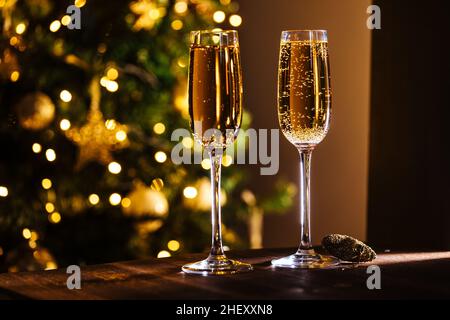 Zwei Gläser Champagner mit weihnachtlichen festlichen Lichtern vor verschwommenem Hintergrund. Feierlaune und Nahaufnahme Stockfoto